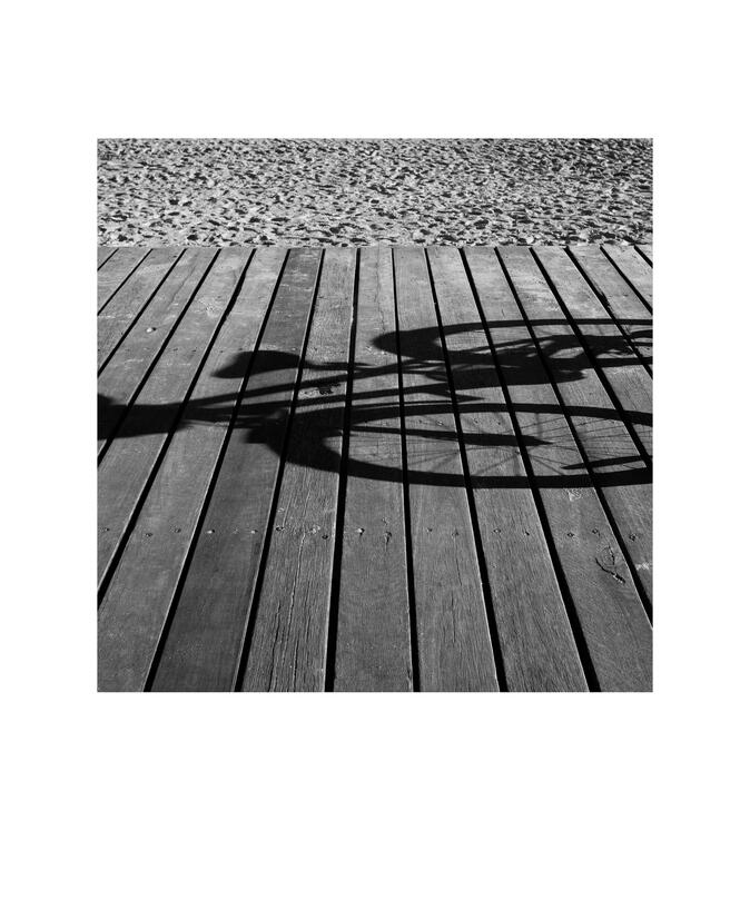 Black and white photograph by Bradley Cummings titled BOARDWALK AND BICYCLE SHADOW, St Kilda, Melbourne, 2022